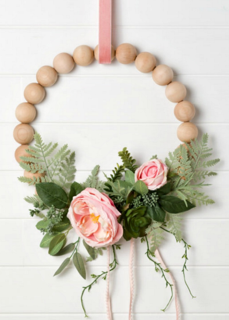wood wreath with greenery and pink flowers