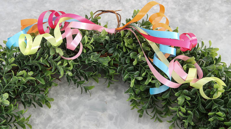 curly ribbon tied to boxwood wreath