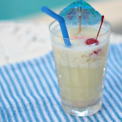 pina colada in tall glass with umbrella and cherry