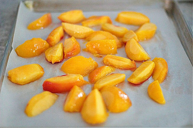 sliced peaches laying on sheet pan