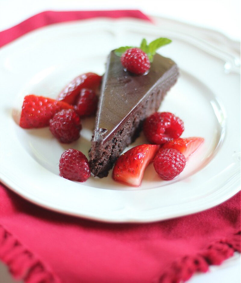 slice of Chocolate Cassis cake with strawberries and raspberries on a white plate