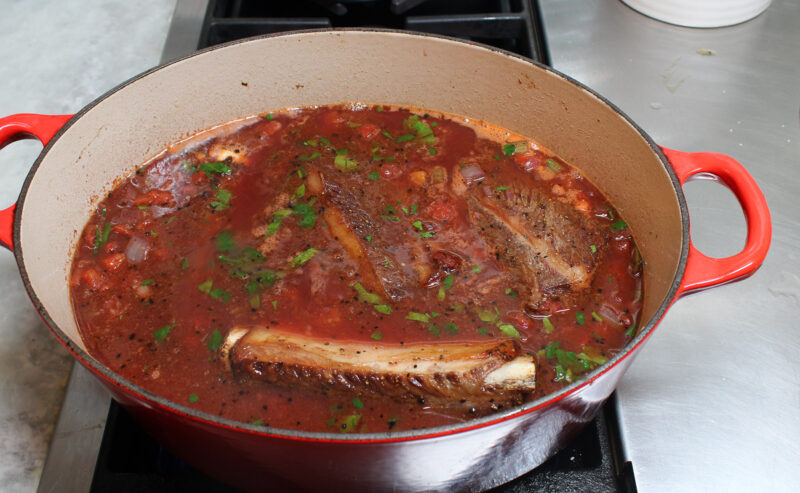 added broth and wine to beef short ribs with tomatoes and ribs