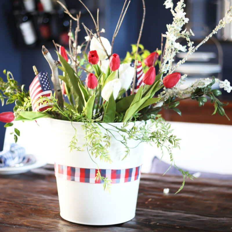 white container filled with red tulips and white flowers with American flags