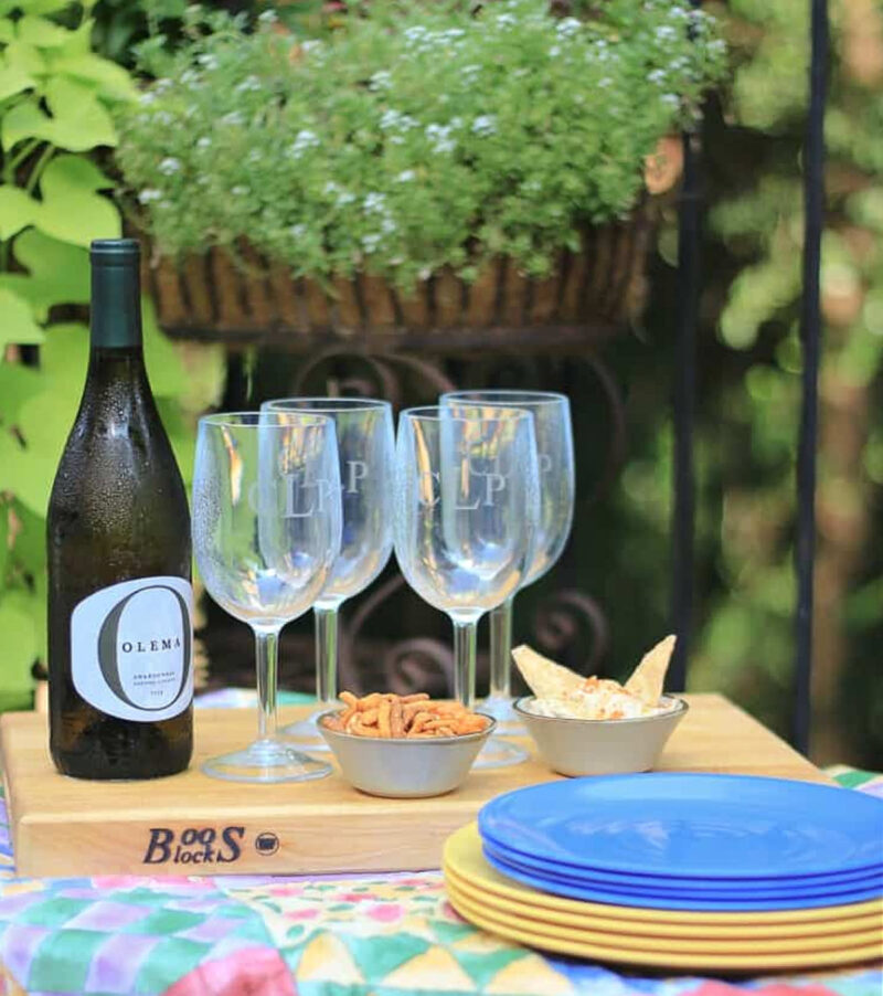 summer picnic with wine glasses, bottle of wine, plates, and snacks
