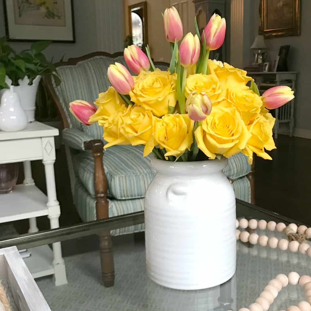 yellow roses and pink tulips in a white vase
