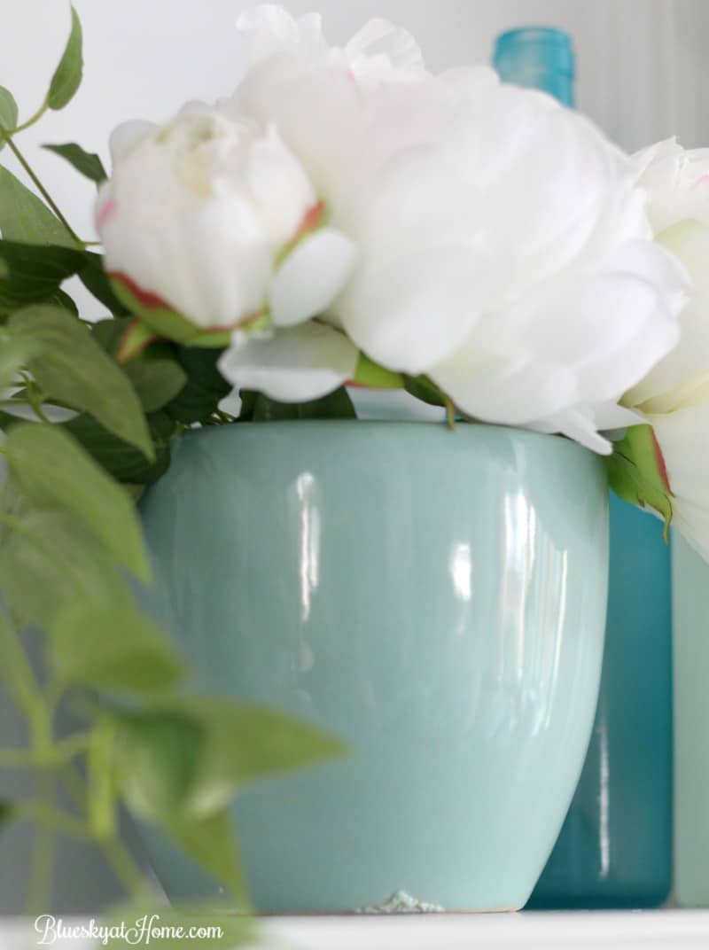 aqua planter with white flower on mantel