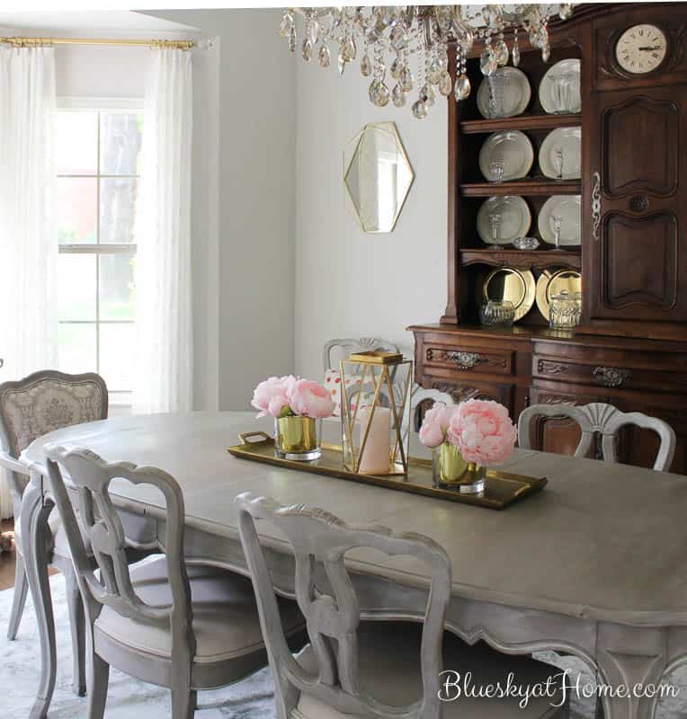 dining room table with flowers in gold containers