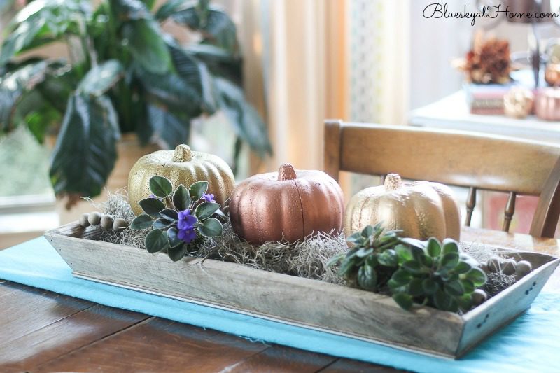 metallic pumpkins in rustic tray on table