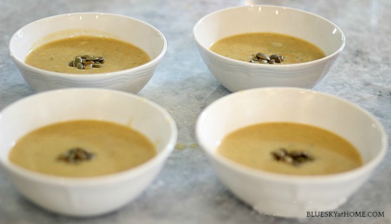 4 bowls of pumpkin soup in white bowls