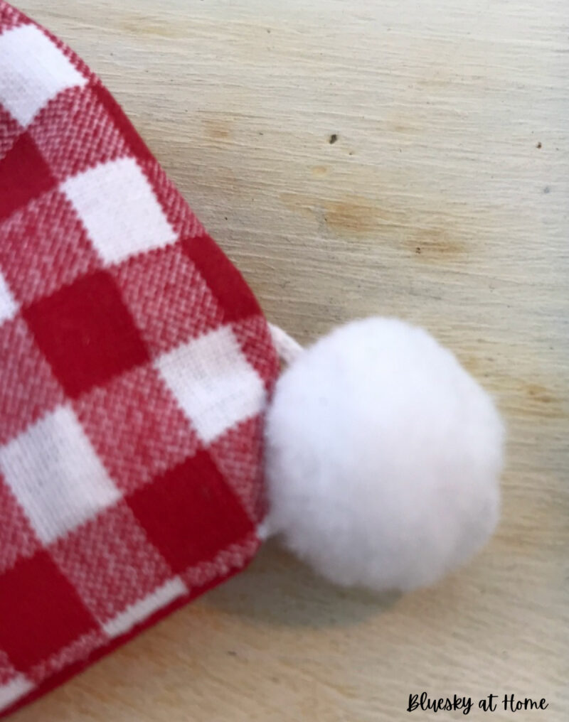 white pom-pom sewed to red check fabric