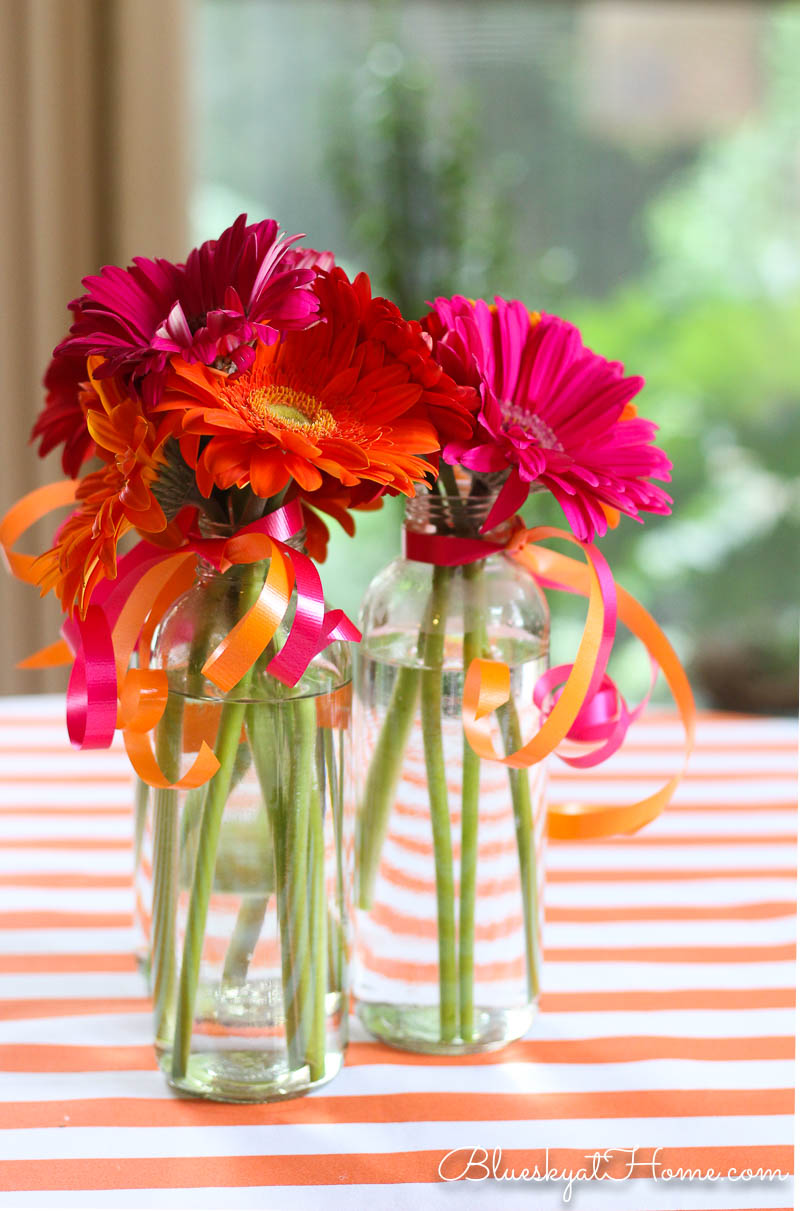 pink gerber daisies in glass bottle