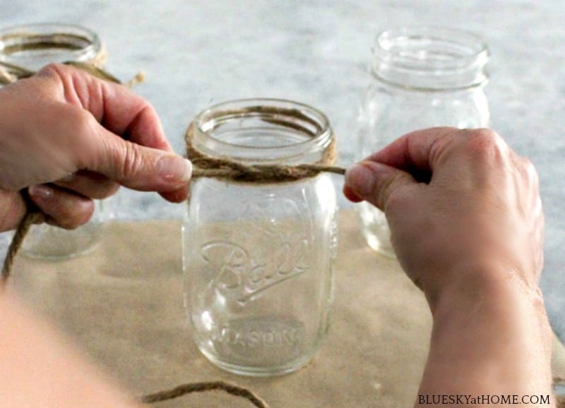 tying twine around mason jars for barbecue DIY project