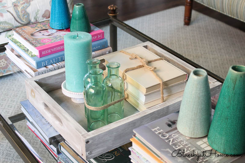stacked books, green bottles and candle in tray