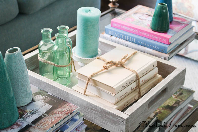 stacked books, green bottles and candle in tray