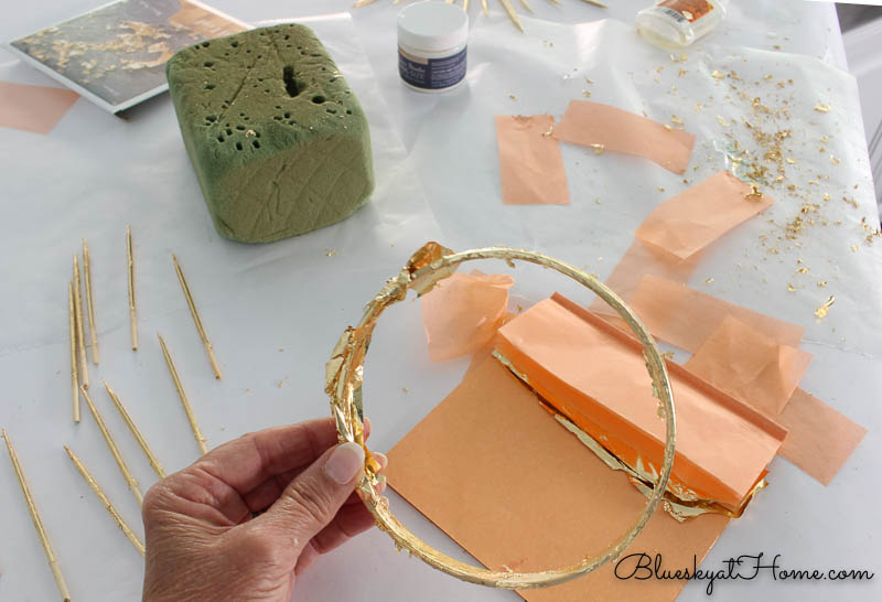 applying gold leaf to embroidery hoop