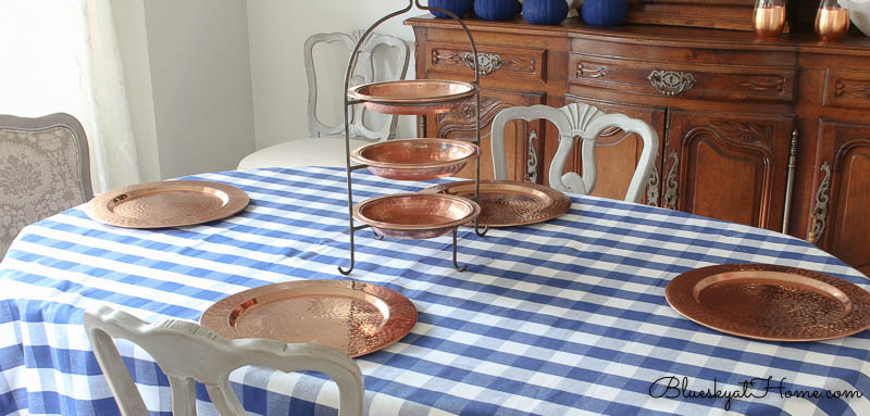copper chargers and copper tiered tray on blue check tablecloth