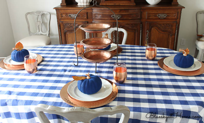 copper chargers and copper tiered tray on blue check tablecloth