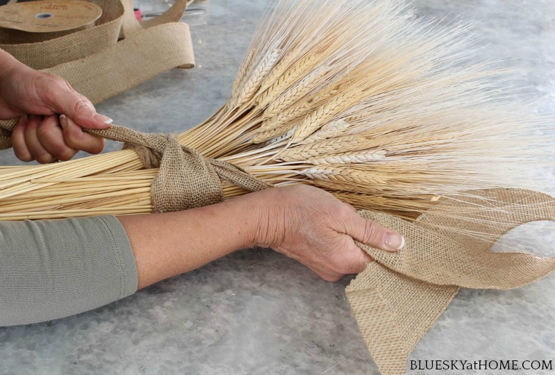 tying bow on wheat bundle