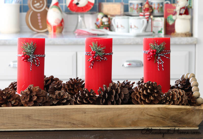 red Christmas candles in tray with pinecones