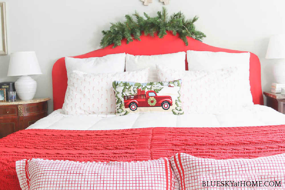 Christmas truck pillows on red and white bed