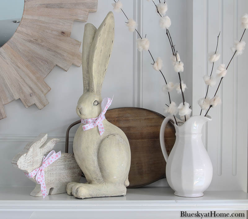 white wood bunnies and white pitcher on mantel