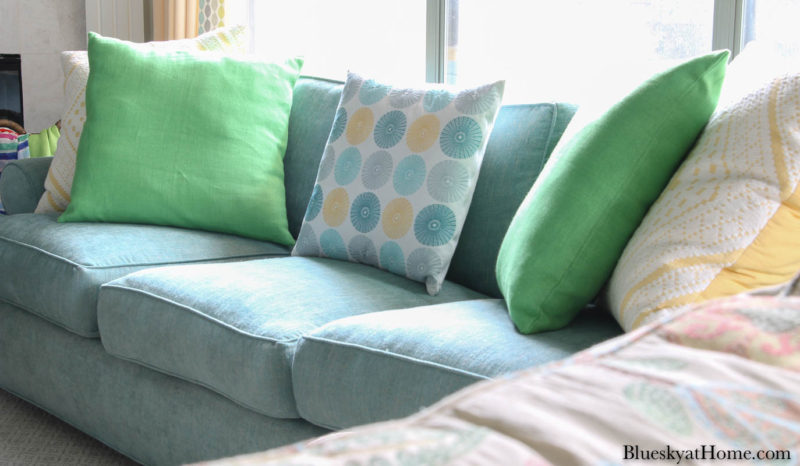 green and yellow pillows on aqua sofa