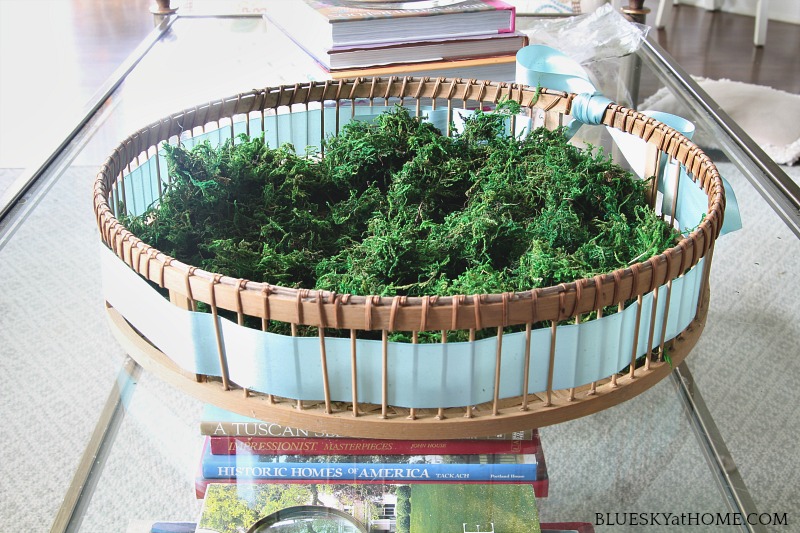basket with blue ribbon and green moss