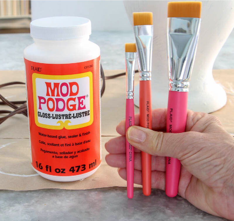 jar of Mod Podge and hand holding three brushes