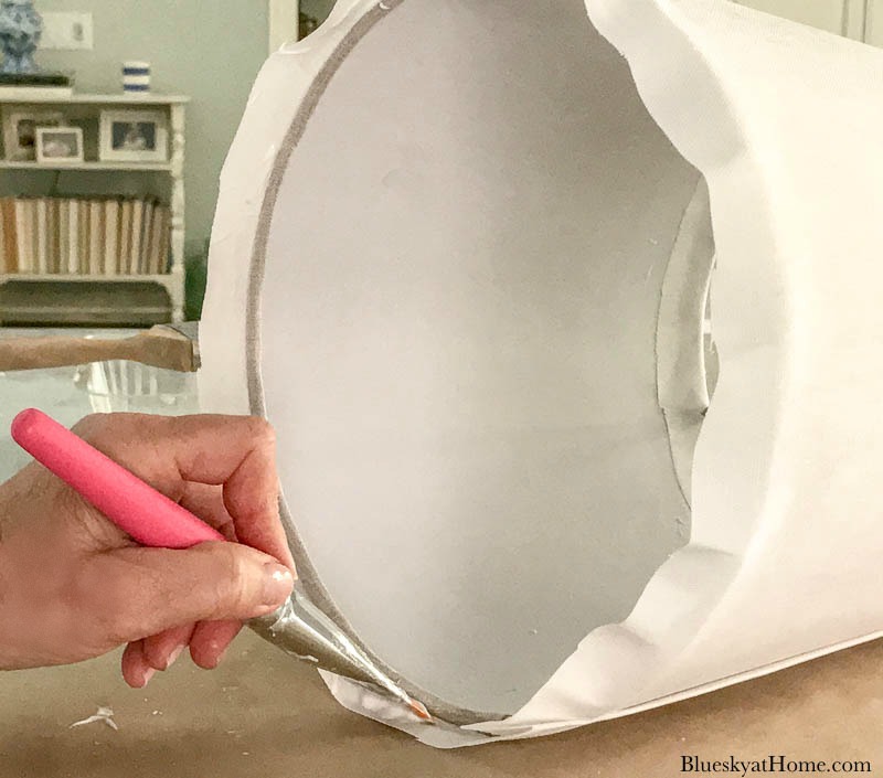 applying Mod Podge to white fabric on lamp shade