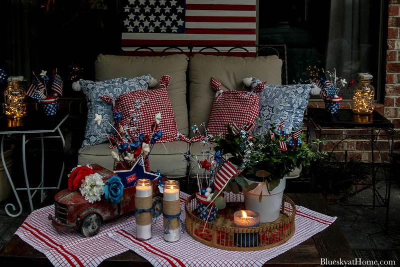 patio loveseat with red and bue pillows and 4th of July decorations at night