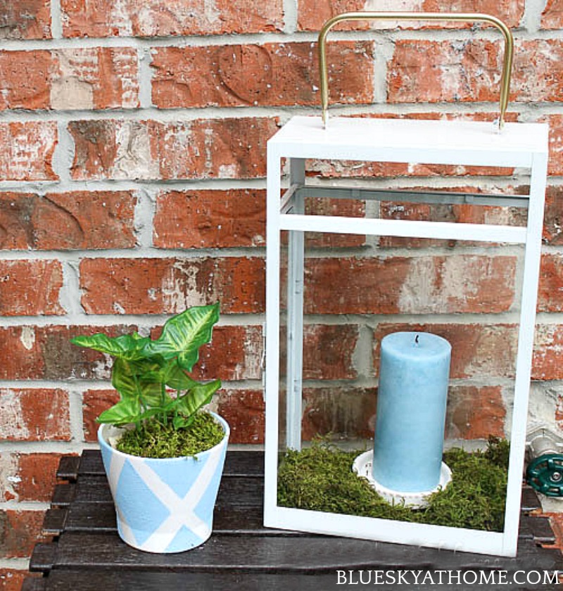 white metal and glass lantern outside with blue candle