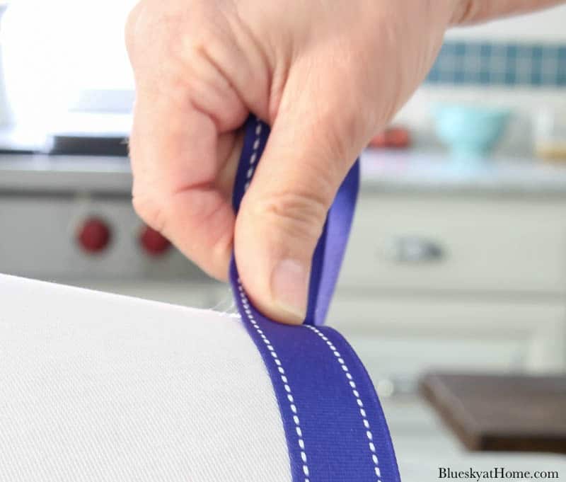 hands holding blue ribbon on white lampshade