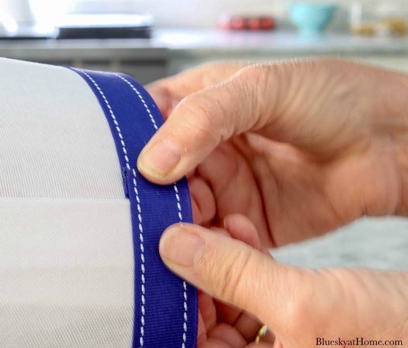 hands holding blue ribbon on white lampshade