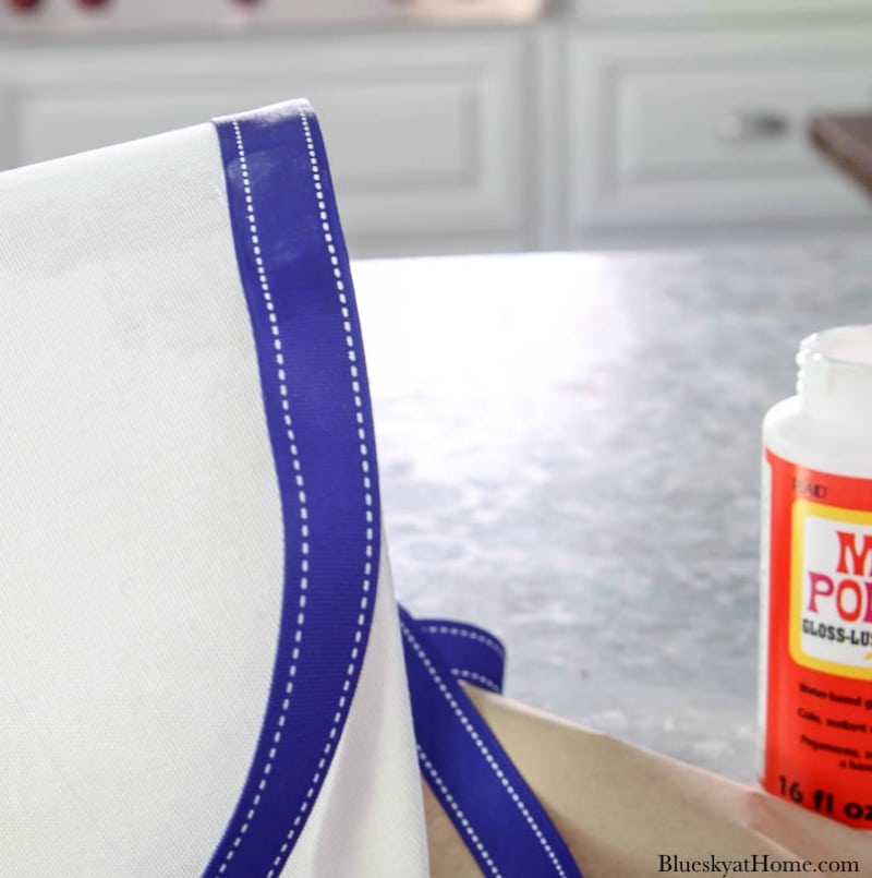 hands gluing blue ribbon on white lampshade