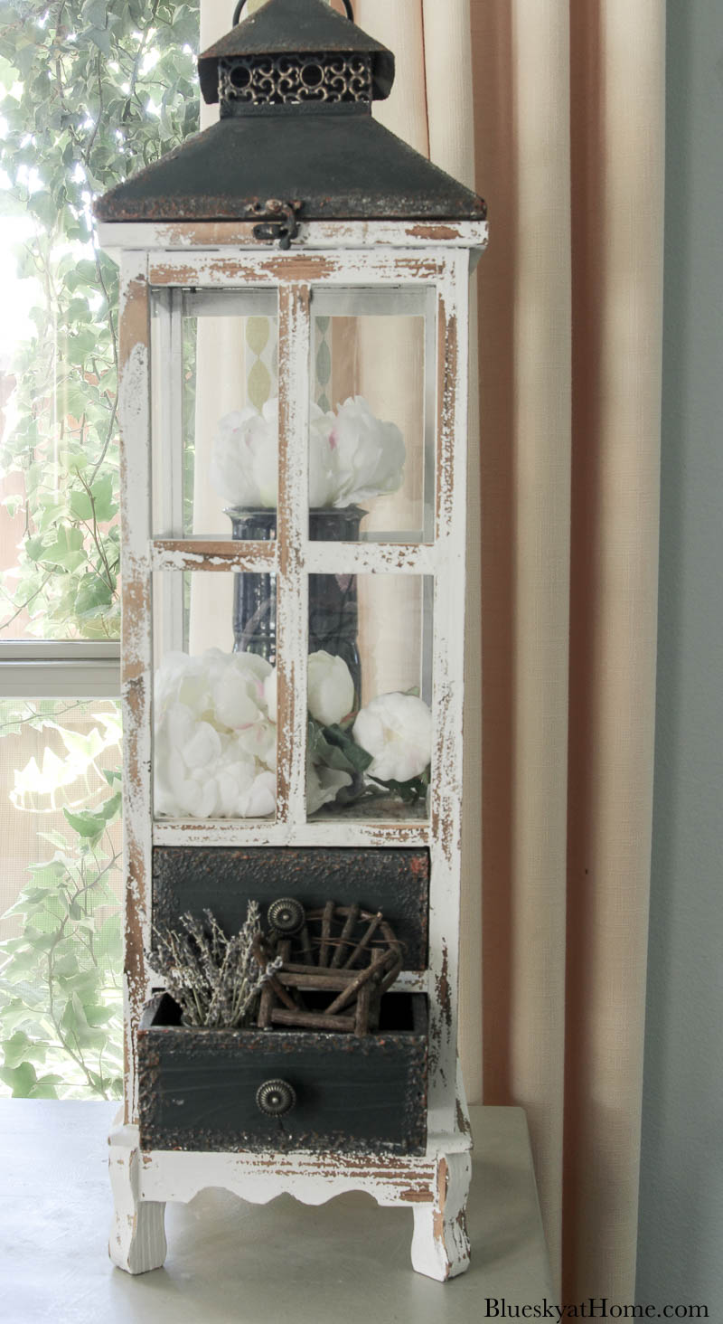 tall wood lantern with blue vase and white flowers