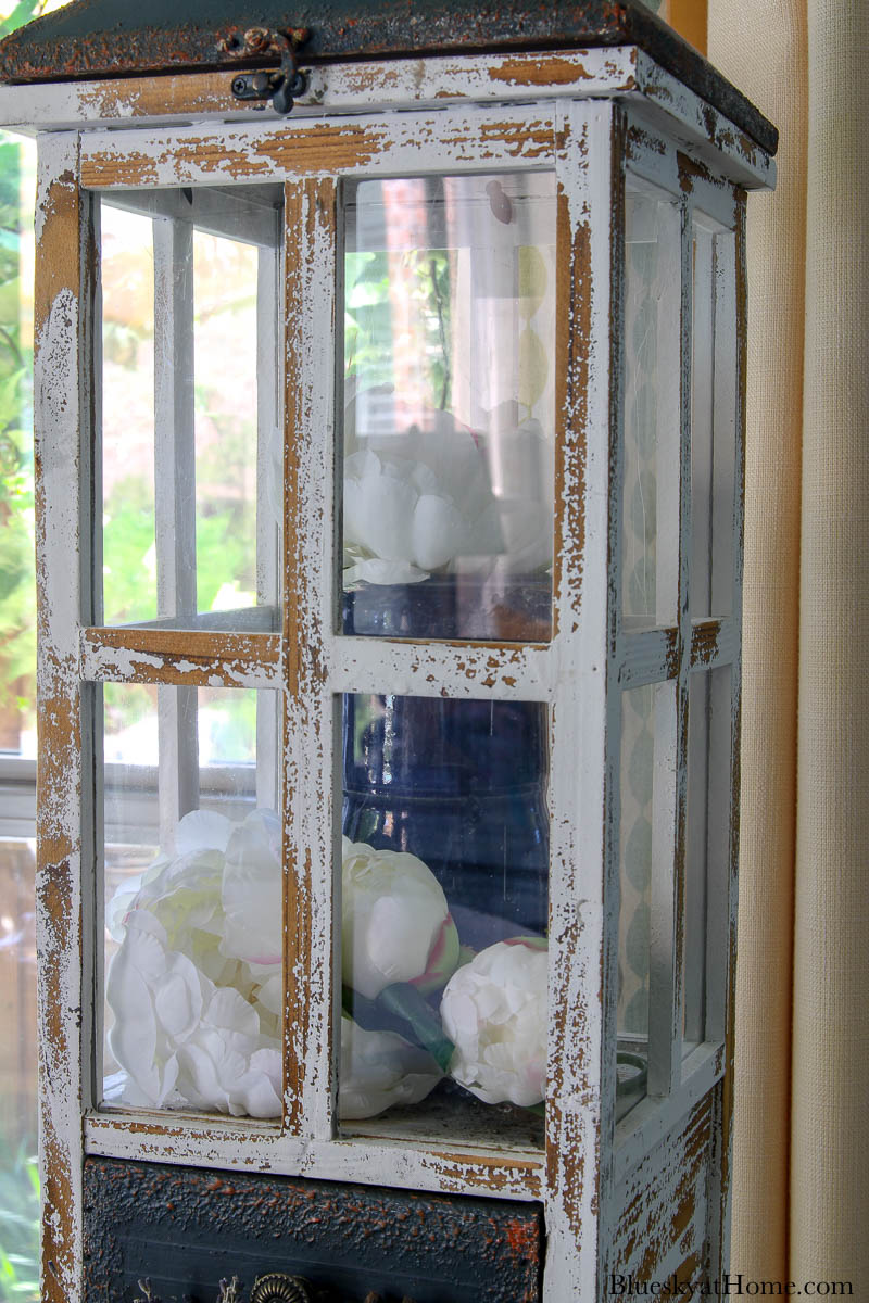 tall wood lantern with blue vase and white flowers