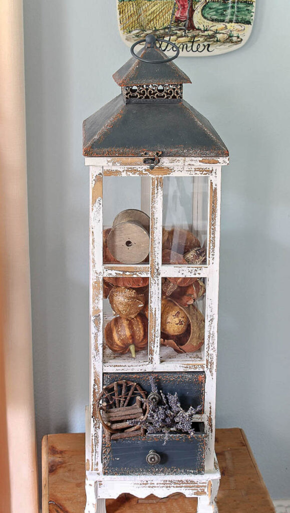 tall wood lantern filled with fall gourds
