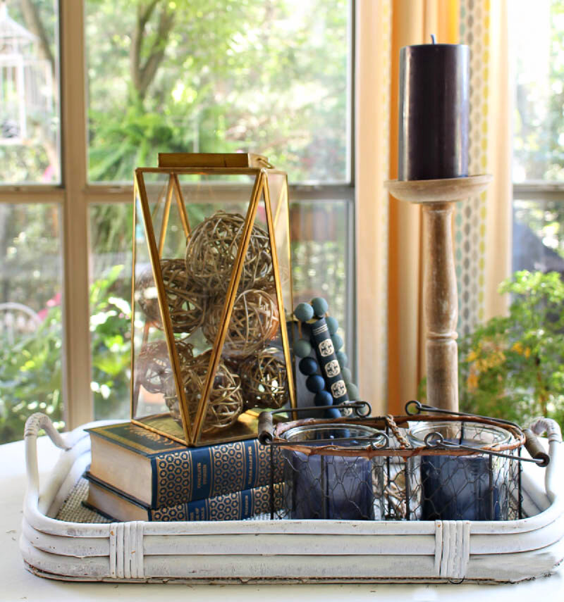brass and glass lantern on stack of blue books in grey tray
