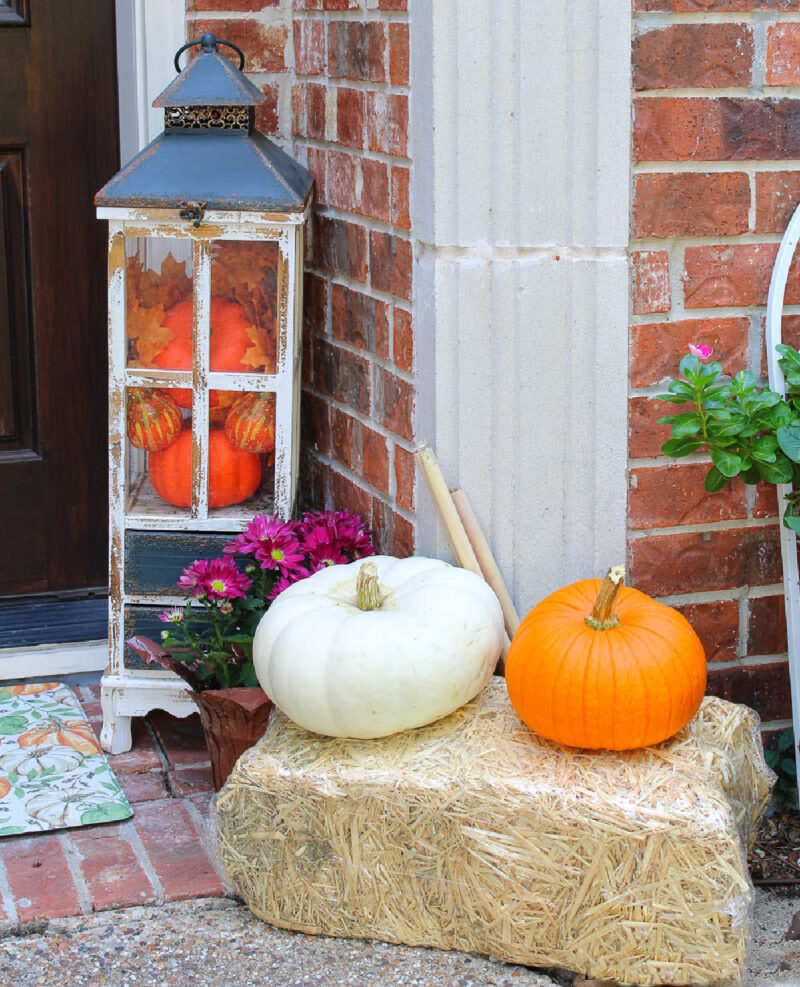 tall wood lantern filled with faux pumpkins