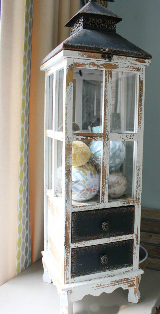 tall wooden lantern filled with fabric-covered balls