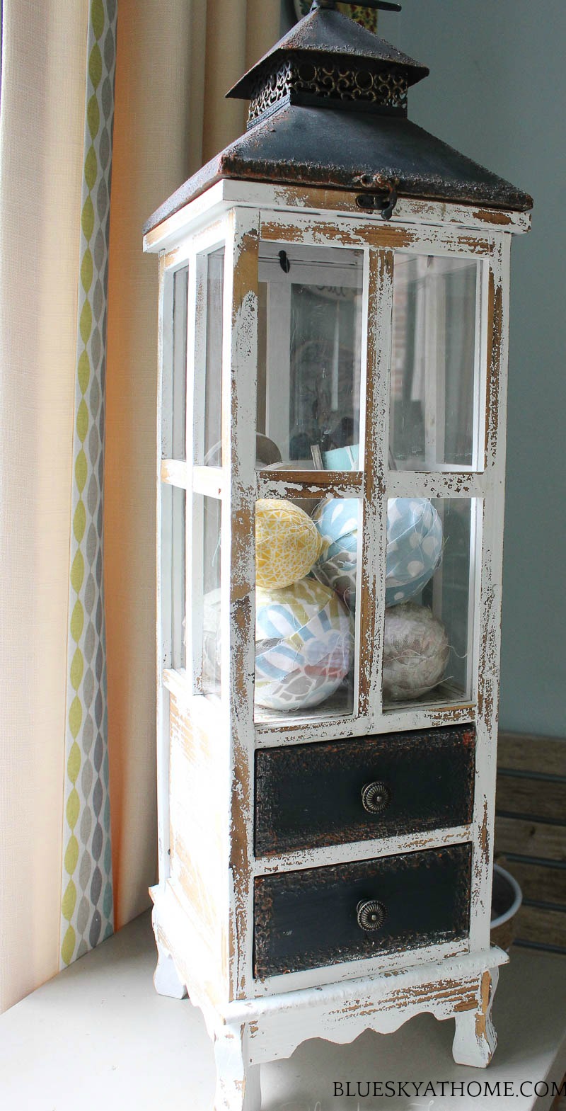 tall wood and glass lantern with fabric balls