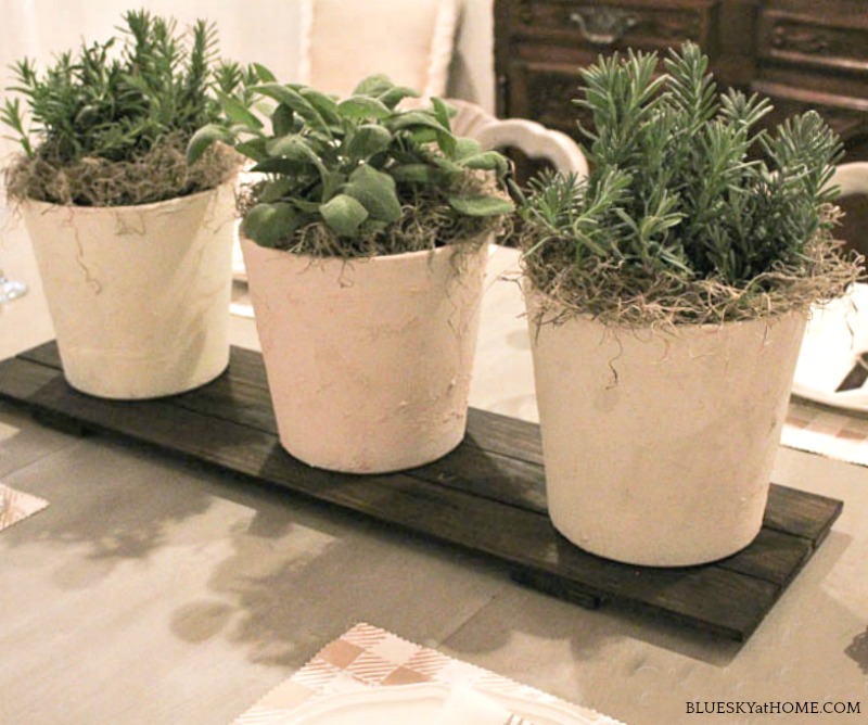 three painted terra cotta pots on dark wood tray.