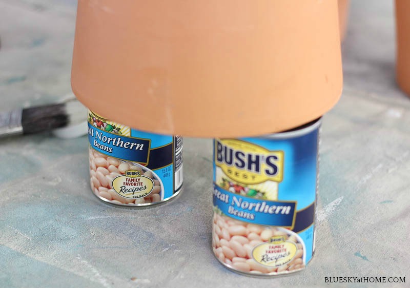 orange terra cotta pot on two cans of beans.