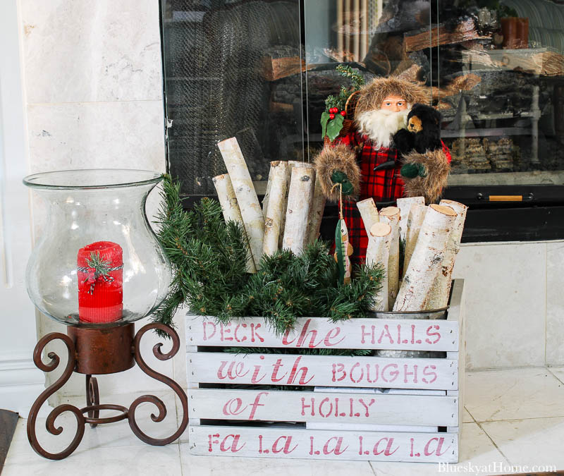 red candle in glass vase with painted crate and Santa