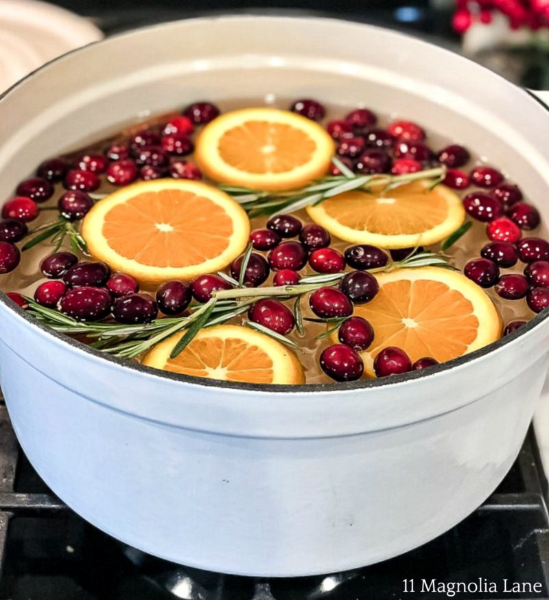 white pot of oranges, cranberries, rosemary