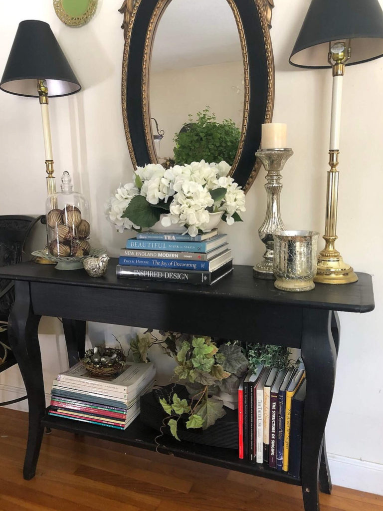 black entry table with white flowers and lamps