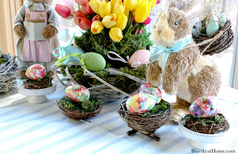 pastel spring flowers in container with bunny and eggs