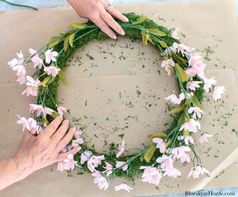 placing pink florals on moss wreath