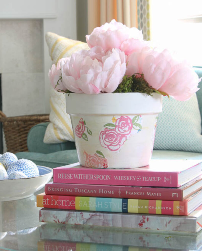 peonies in floral pot on a stack of books on coffee table