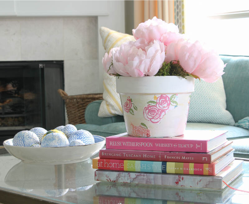 peonies in floral pot on a stack of books on coffee table